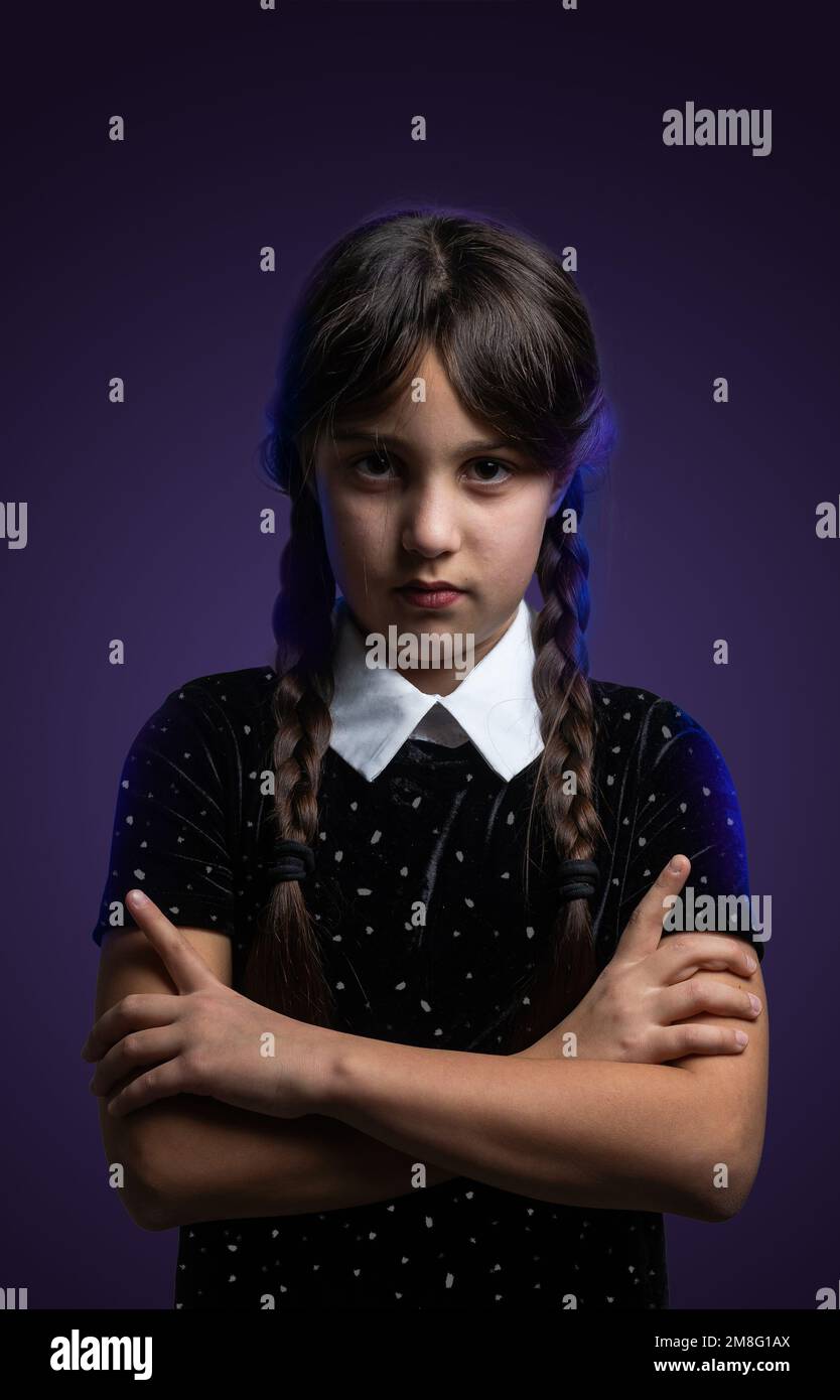 Ritratto di bambina con costume di mercoledì Addams durante Halloween.  Espressione seria e atmosfera scura con sfondo scuro Foto stock - Alamy