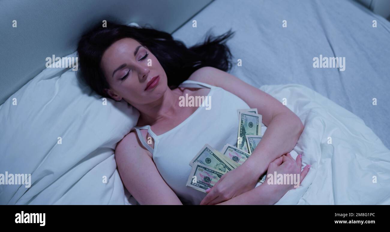 Donna che dorme sul letto con il pacchetto delle note di valuta Foto Stock