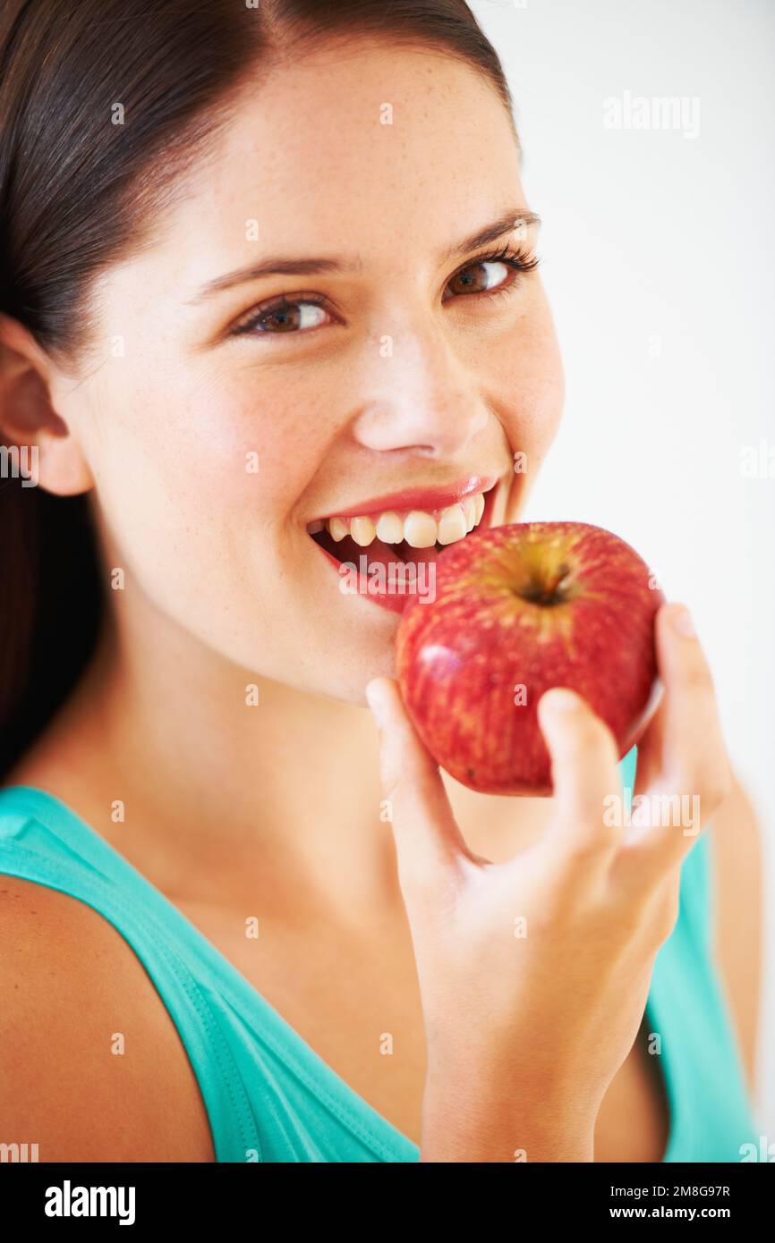 Prendere un boccone da una mela rossa. Ritratto di una bella giovane donna che gode di una mela. Foto Stock