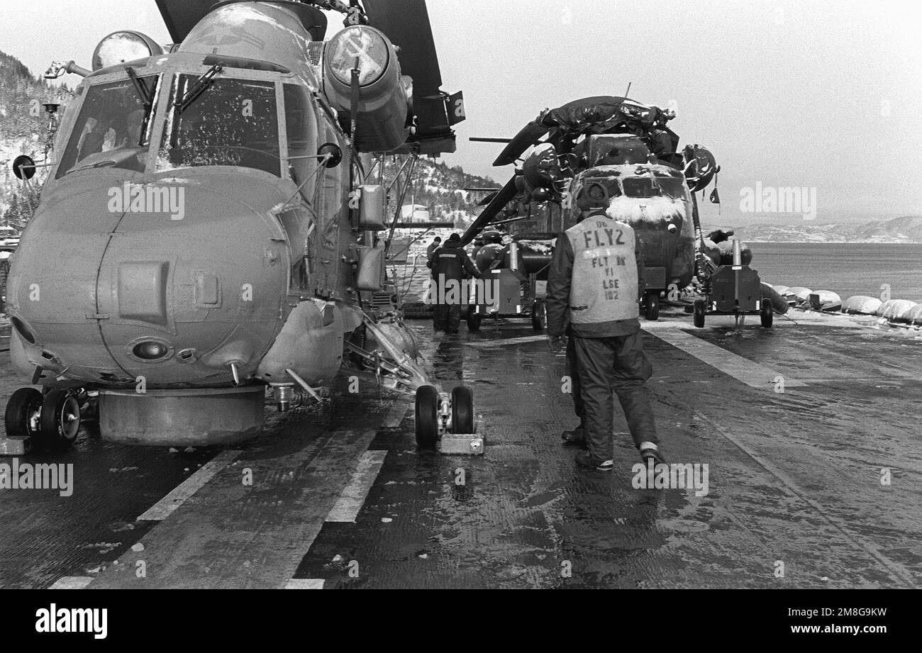 Dopo aver riposto il ponte di volo della copertura di neve, il personale del ponte di volo della nave d'assalto anfibio USS GUADALCANAL (LHP-7) inizia a preparare vari elicotteri per le operazioni di volo. Il CANALE DI GUADALCANAL si trova nel Baltico e partecipa all'esercitazione NATO del lavoro di squadra '92. Subject Operation/Series: LAVORO DI SQUADRA '92 base: Trondheim Fjord Paese: Norvegia (NOR) Foto Stock