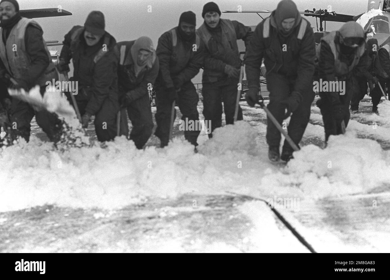 Gli equipenti della nave d'assalto anfibio USS GUADALCANAL (LPH-7) spazzano la neve dal ponte di volo durante le operazioni invernali a sostegno dell'esercizio NATO Teamwork '92. Subject Operation/Series: LAVORO DI SQUADRA '92 base: Trondheim Fjord Paese: Norvegia (NOR) Foto Stock