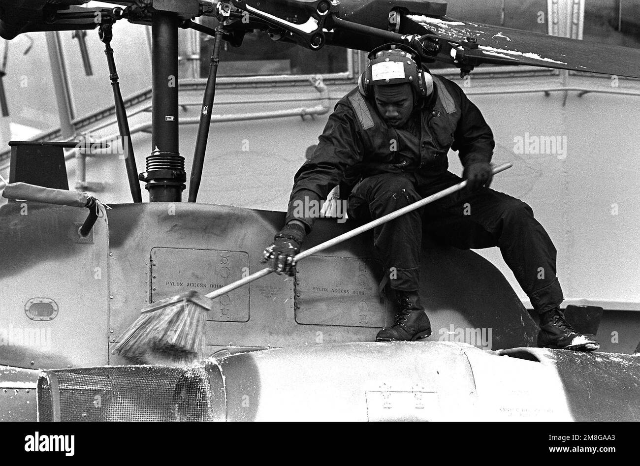 Un marinaio spazzola la neve dalla cima di un elicottero AH-1W Super Cobra sul ponte di volo della nave d'assalto anfibio USS GUADALCANAL (LPH-7) durante le operazioni invernali a sostegno della NATO Esercitazione Teamwork '92. Subject Operation/Series: LAVORO DI SQUADRA '92 base: Trondheim Fjord Paese: Norvegia (NOR) Foto Stock