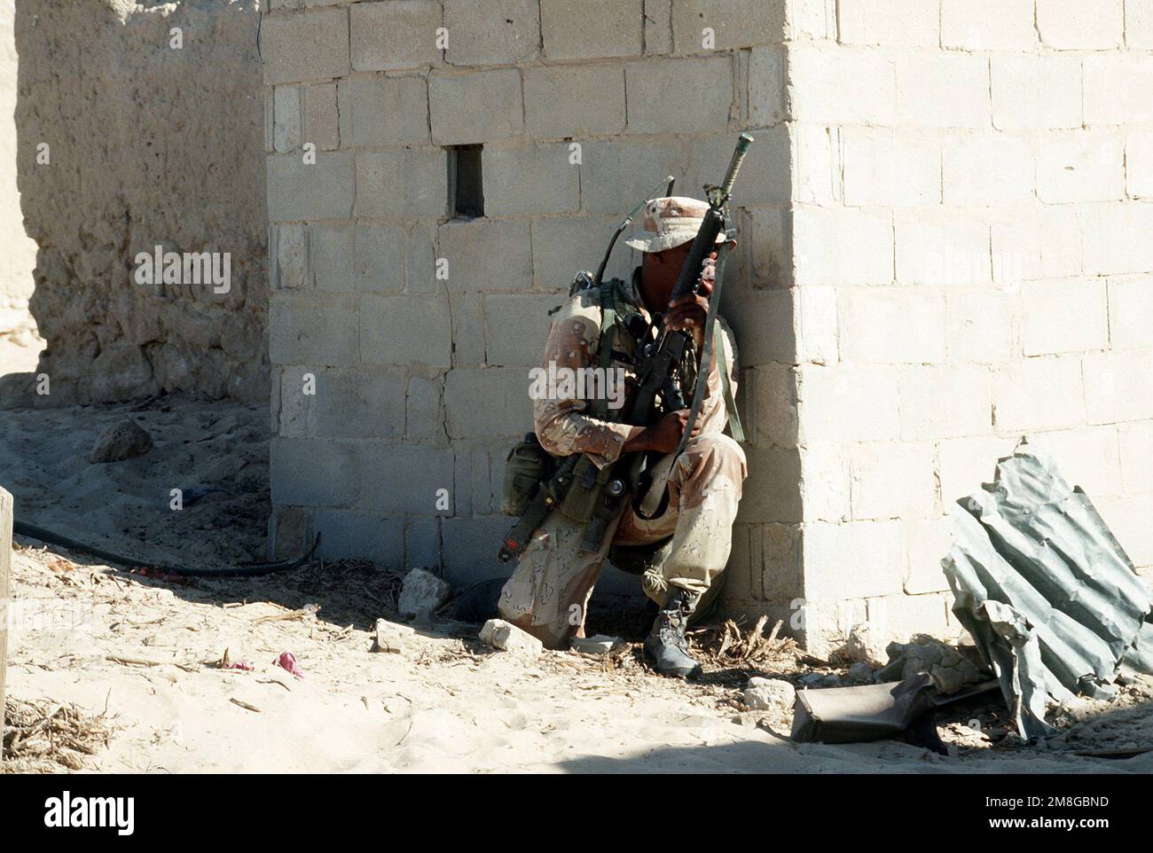 Un soldato di Co.. A, 3rd BN., 502nd INF. Regt., 101st Airborne Div., guarda dal suo punto panoramico dietro un muro mentre partecipa a un allenamento di guerra urbano in una città abbandonata durante l'operazione Desert Shield. Il soldato è armato di un fucile M-16A2. Subject Operation/Series: SCUDO DEL DESERTO Paese: Arabia Saudita (SAU) Foto Stock