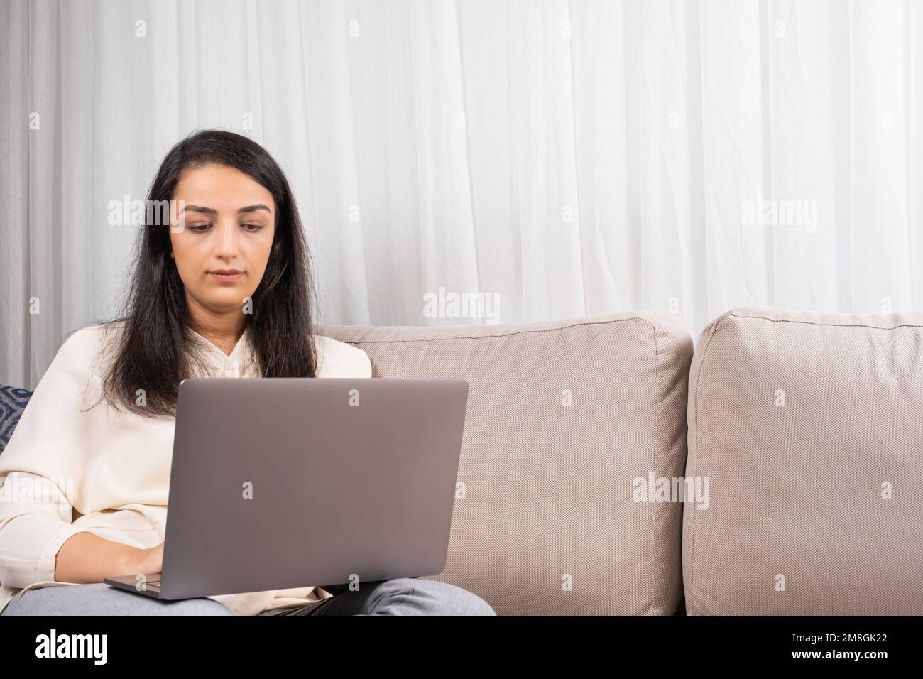 Donna che utilizza un notebook, divano, scrivere e-mail, partecipare a una riunione online, guardare il webinar, studiare idea di concetto. Foto Stock