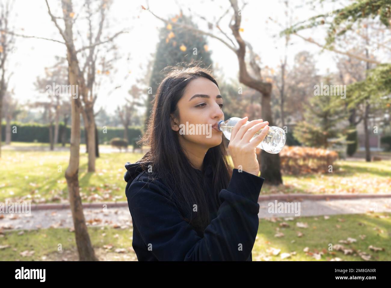 Vista di profilo di donna sportiva acqua potabile. Bottiglia di vetro. Passeggiate o jogging. Spazio di copia. Ragazza in forma godendo di acqua. Idea di concetto di stile di vita. Foto Stock Vista di profilo di donna sportiva acqua potabile. Bottiglia di vetro. Passeggiate o jogging. Spazio di copia. Ragazza in forma godendo di acqua. Idea di concetto di stile di vita. Foto Stock
