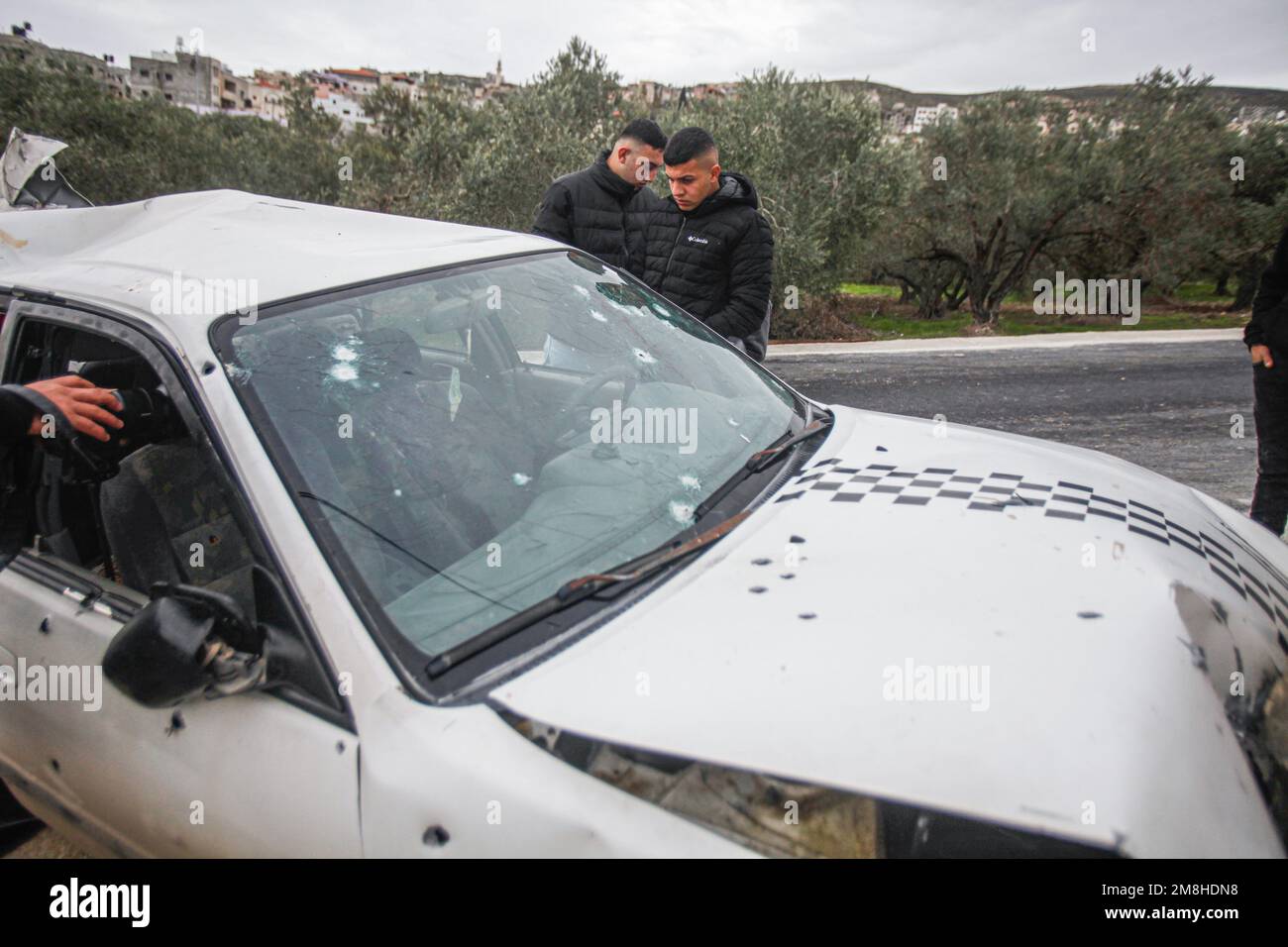 Jenin, Palestina. 14th Jan, 2023. I palestinesi ispezionano l'auto in cui due palestinesi sono stati uccisi dall'esercito israeliano durante il loro inseguimento, dopo aver aperto il fuoco su un posto militare, nella città di Jaba, vicino a Jenin, nella Cisgiordania occupata. Credit: SOPA Images Limited/Alamy Live News Foto Stock