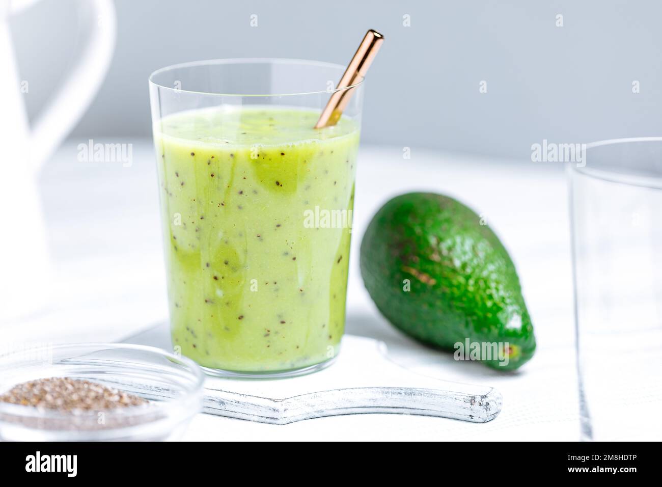 Frullato verde in vetro servito con paglia. Prodotto con semi di kiwi e chia. Super cibo e antiossidante per uno stile di vita sano Foto Stock