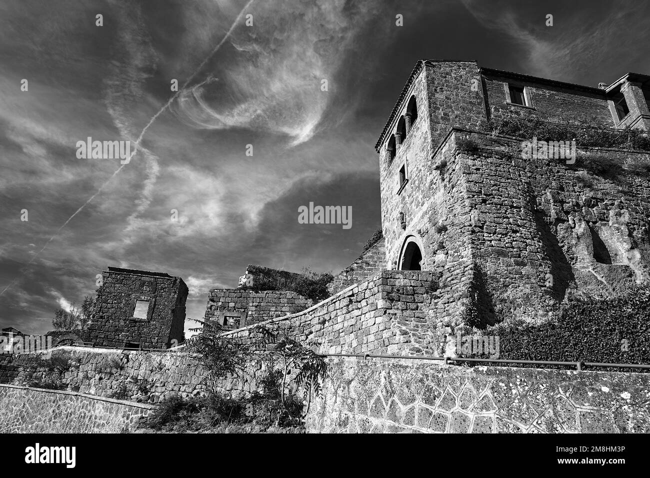 Edifici in pietra con porta alla storica città di Bagnoregio, Italia, monocromatici Foto Stock