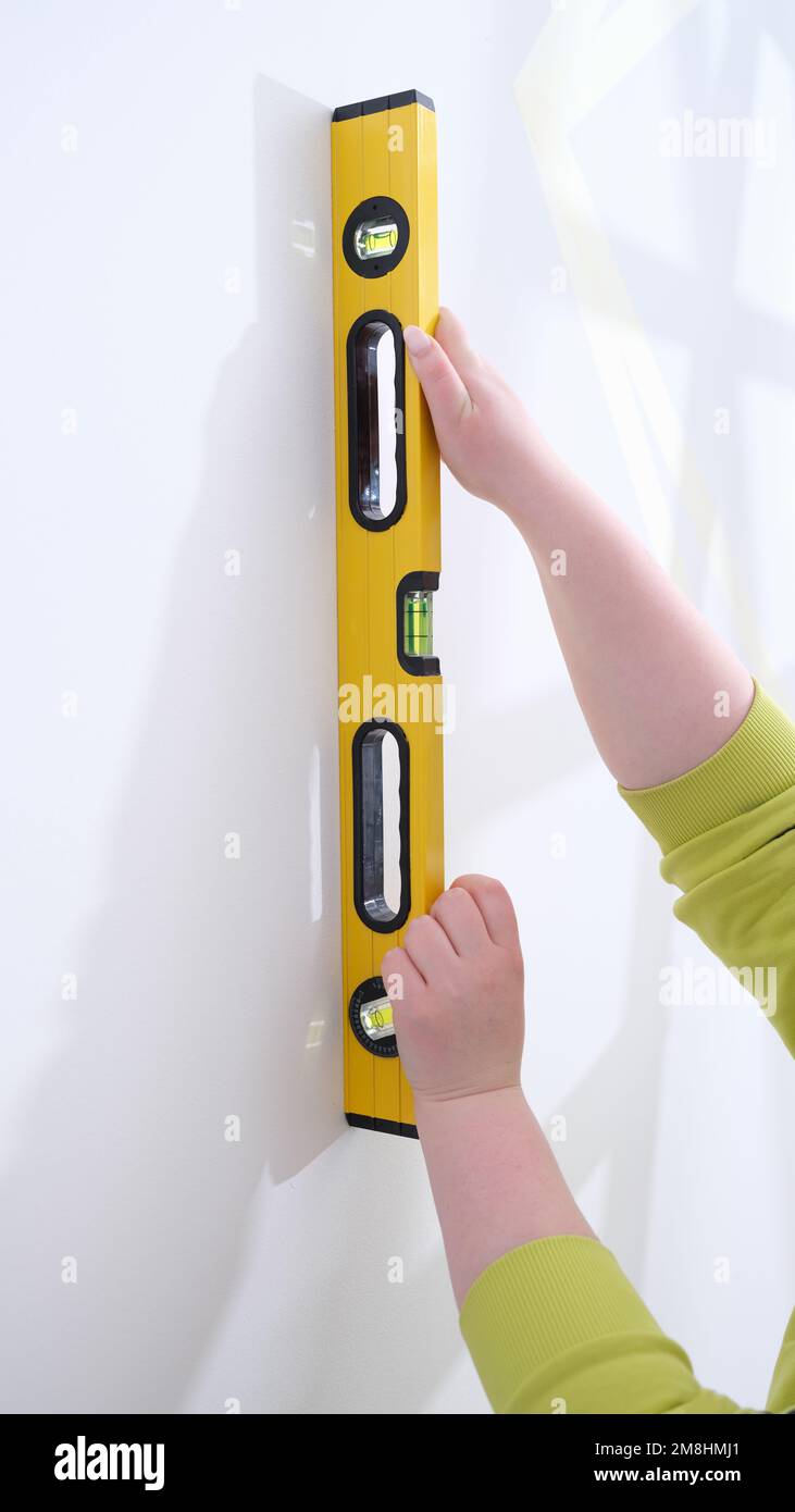 Le mani di lavoro controllano l'uniformità della parete con l'attrezzo speciale per la misurazione del livello Foto Stock