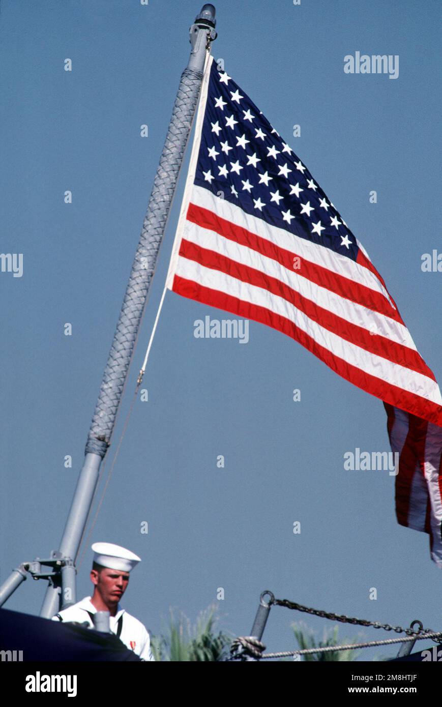 Un marinaio si trova accanto alla firma nazionale sulla poppa della fregata USS LOCKWOOD (FF-1064) durante la cerimonia di smantellamento della nave. Base: Naval Air Station, San Diego Stato: California (CA) Paese: Stati Uniti d'America (USA) Foto Stock