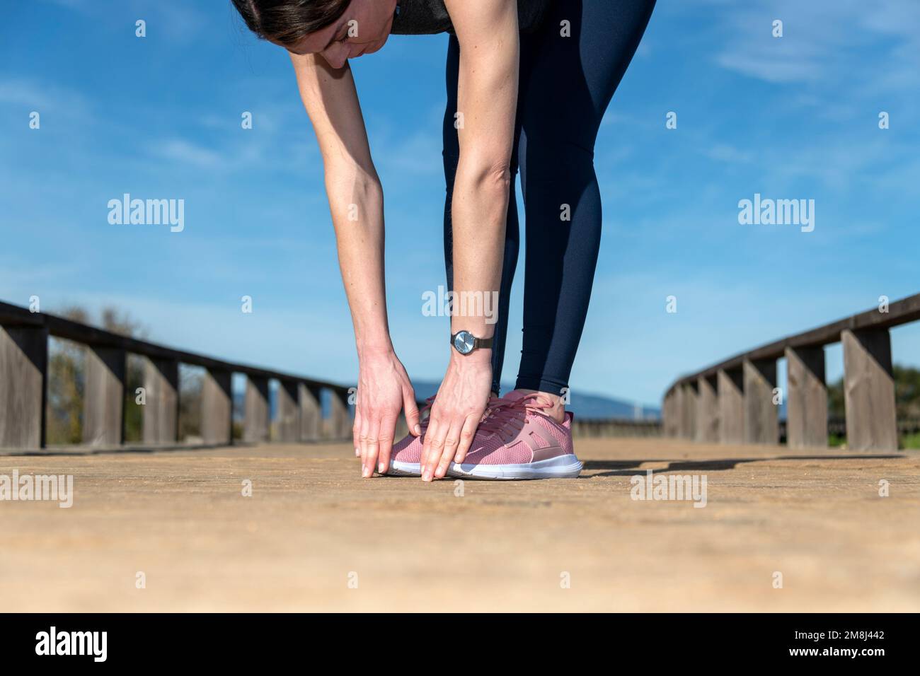 Primo piano di una donna sportiva che tocca le dita dei piedi, scalda gli esercizi all'esterno. Foto Stock