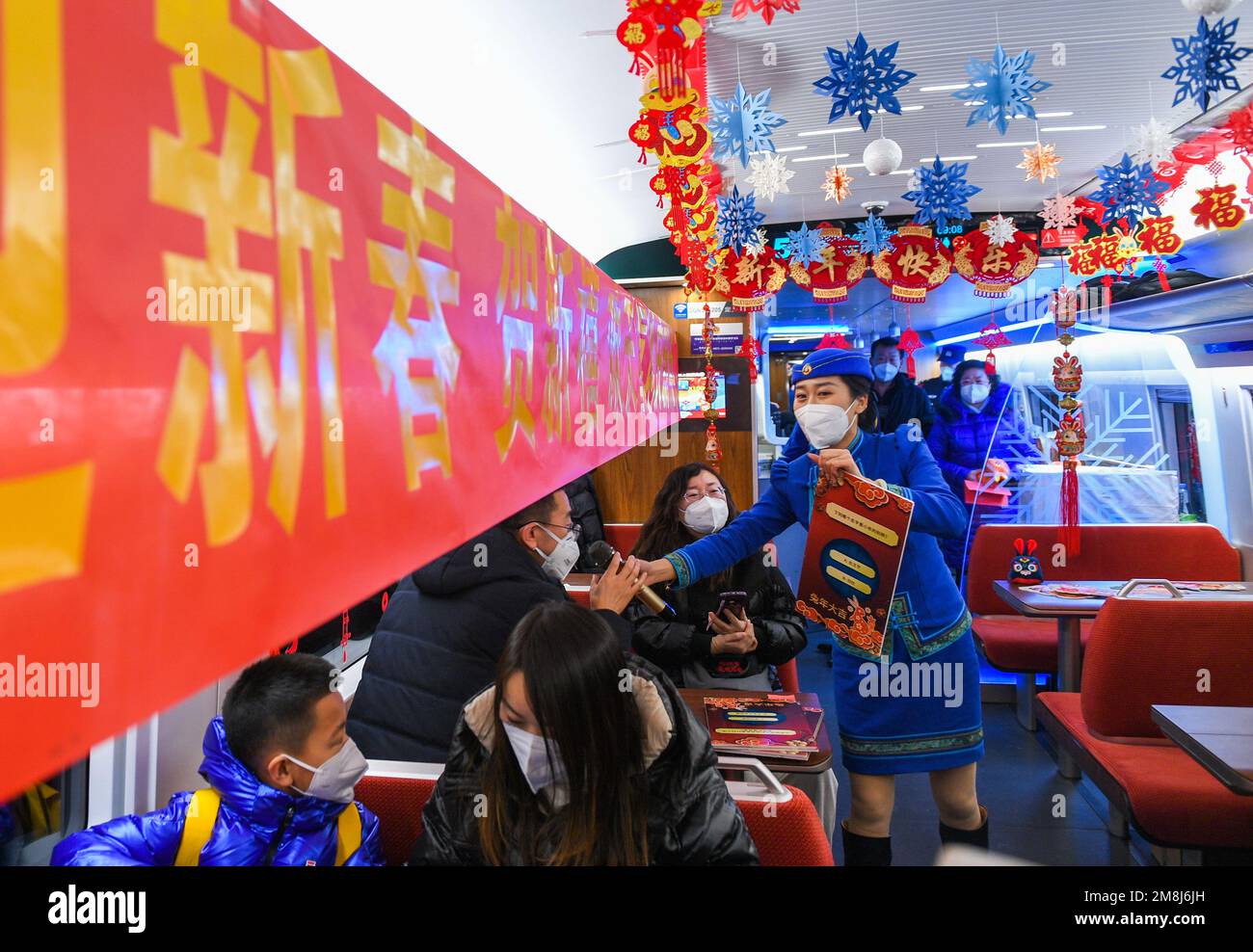 Hohhot, da Pechino a Hohhot. 14th Jan, 2023. Un passeggero gioca un quiz sul treno superveloce Fuxing G2457, che viaggia da Pechino a Hohhot, il 14 gennaio 2023. Il tradizionale festival cinese Xiaonian, che segna l'inizio del conto alla rovescia per il Capodanno cinese lunare, cade il sabato nel nord della Cina. Gli steward e i membri della troupe di Ulan Muqir hanno presentato regali ai passeggeri e si sono esibiti sul treno per celebrare il festival di Xiaonian. Credit: Liu Lei/Xinhua/Alamy Live News Foto Stock