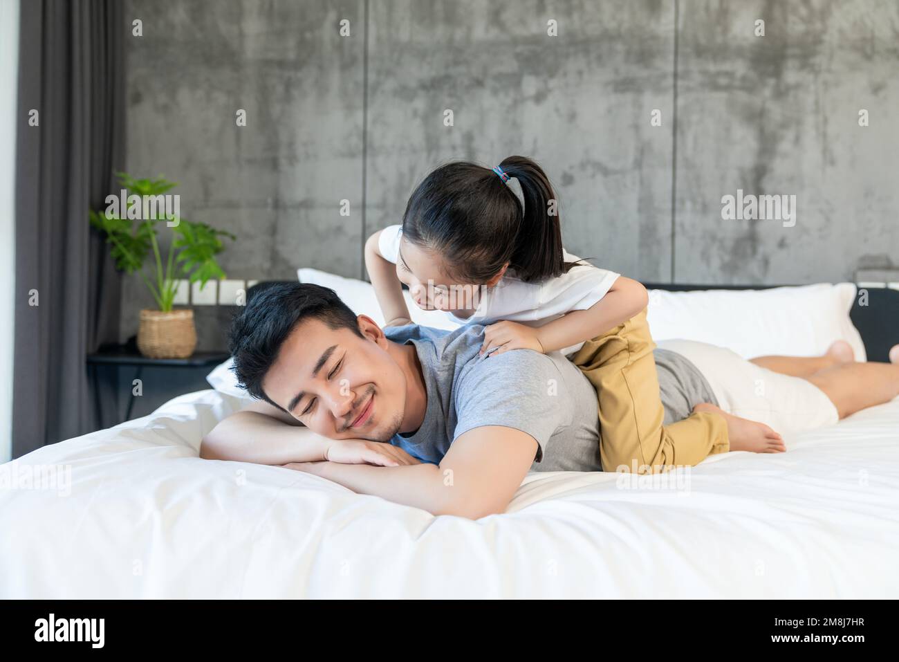 Felice giovane padre e figlia che giocano sul letto Foto Stock