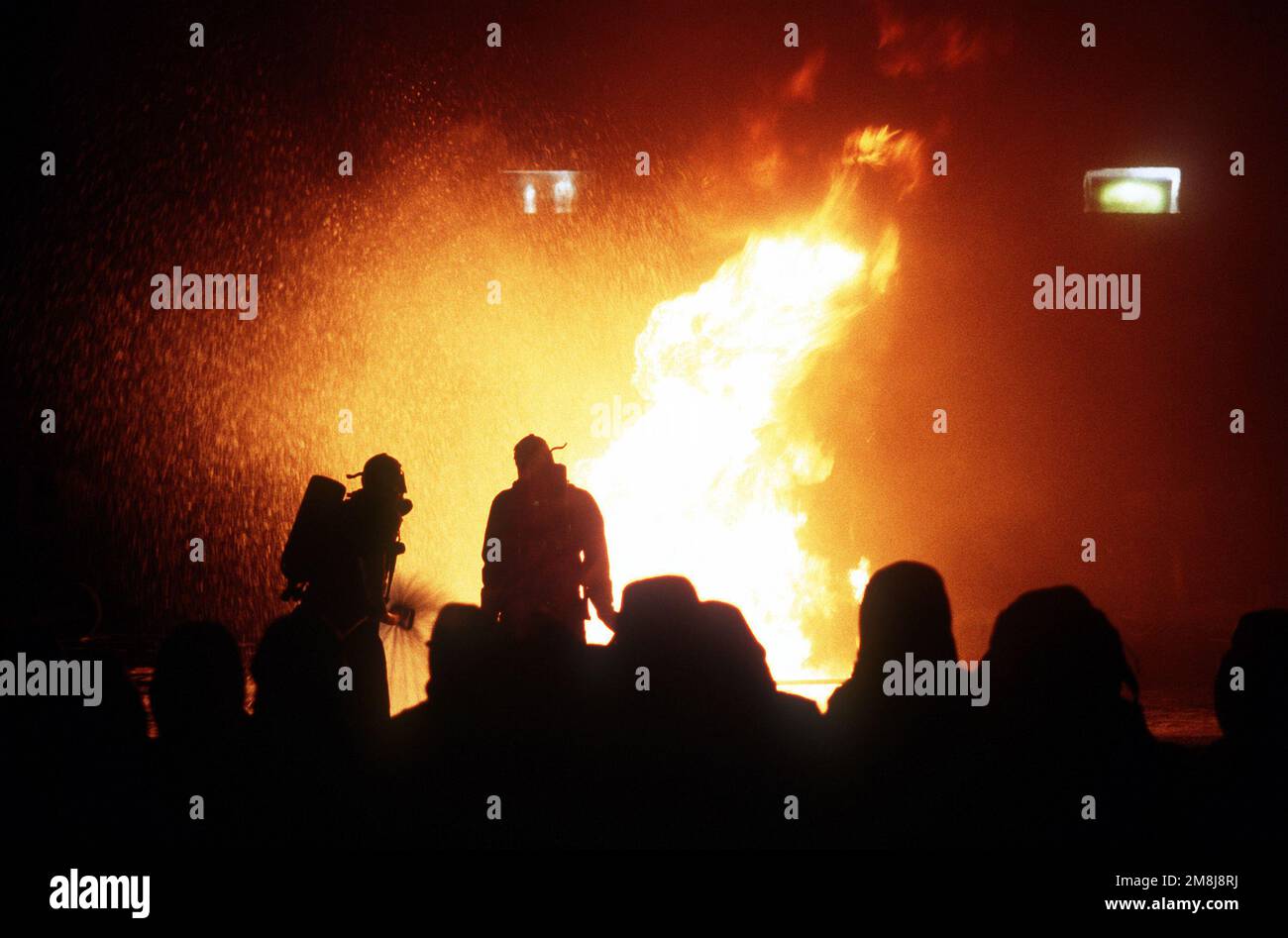 Gli studenti che combattono gli aerei (in primo piano) osservano gli istruttori che estinguono un fuoco di armi simulate presso la Navy Fire Fighting School, Naval Station di San Diego. Base: San Diego Stato: California (CA) Paese: Stati Uniti d'America (USA) Foto Stock