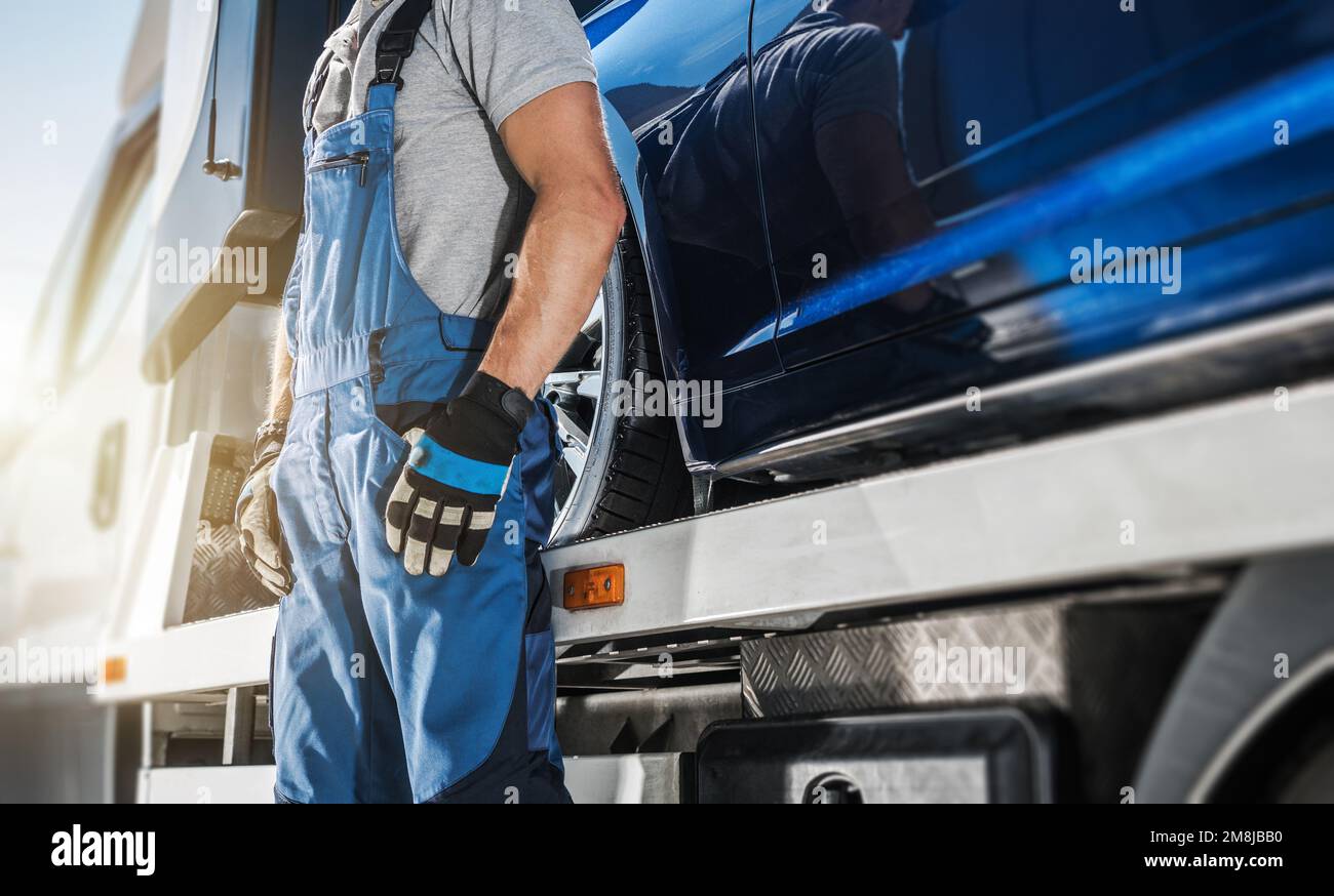 Conducente di camion di traino professionale che rimane accanto al suo veicolo. Primo piano della parte inferiore della carrozzeria. Industria dei trasporti. Foto Stock