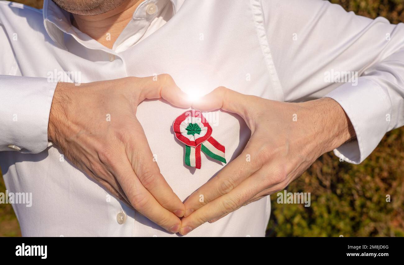 uomo plea una camicia bianca con rosetta tricolore simbolo della giornata nazionale ungherese 15th marzo mani vacanza a cuore a forma di cerchio con la rosetta Foto Stock