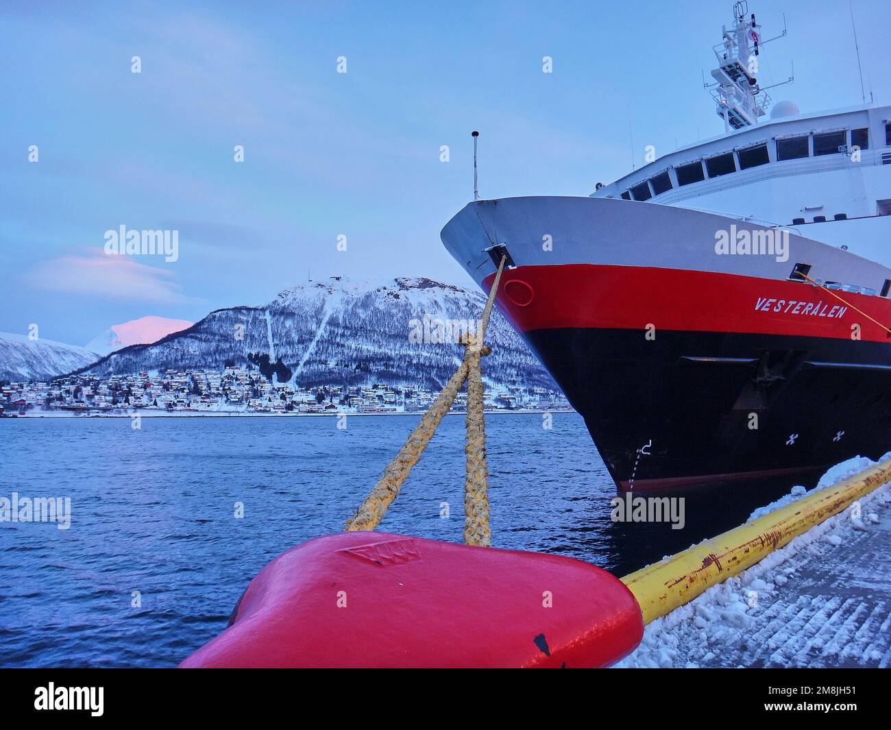 Tromso, Norvegia - 03 13 2013: Hurtig rotte posta e nave da crociera nel paesaggio invernale del porto di Tromso in un fiordo sulla costa settentrionale Foto Stock