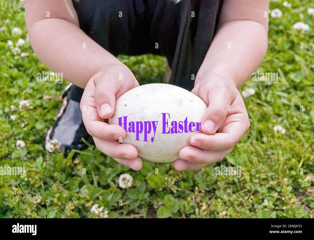 Bambina che tiene un uovo bianco con il testo viola felice di Pasqua Foto Stock