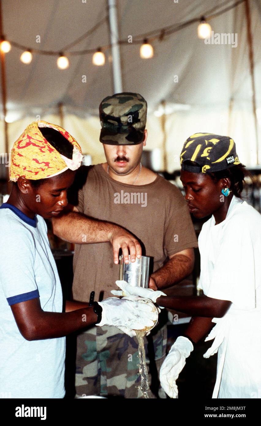 SPC. Phillips, US Army, Hunter Army Airfield, Fort Stewart, Georgia, Aiuta a preparare i pasti con i rifugiati haitiani che si sono offerti volontariamente di cucinare nella tenda del caos del McCallah Field. Subject Operation/Series: SEA SIGNAL base: Guantánamo Bay Paese: Cuba (CUB) Foto Stock