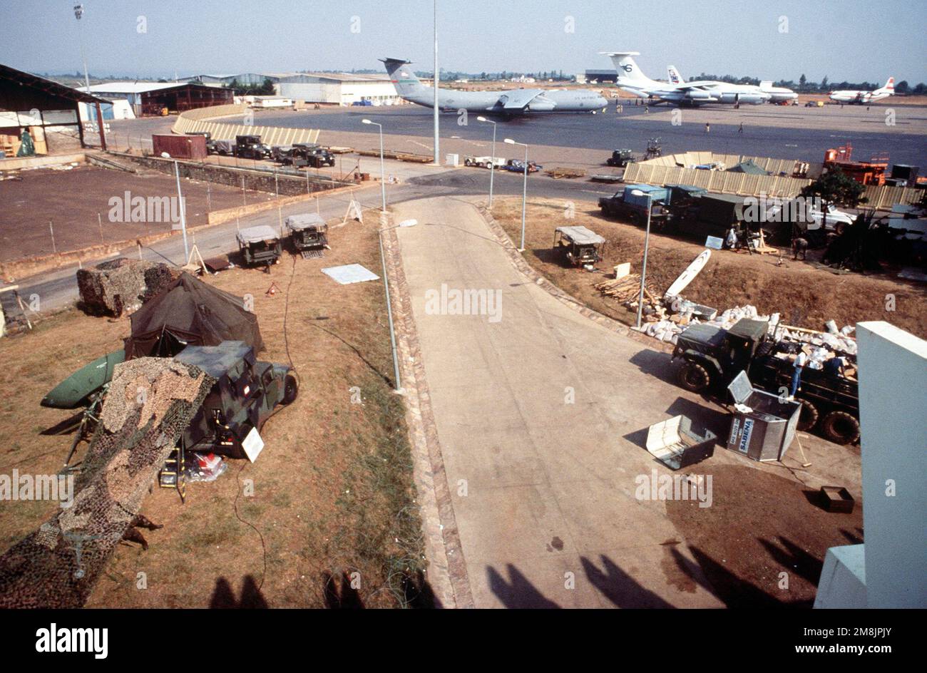 Vista generale dell'Aeroporto Internazionale di Kigali. Le apparecchiature tattiche per le comunicazioni via satellite sono in primo piano a sinistra e sullo sfondo si possono vedere un aereo Starlifter C-141 dell'aviazione militare statunitense e altri aerei commerciali. Subject Operation/Series: RIPRISTINARE LA SPERANZA base: Kigali Paese: Ruanda (RWA) Foto Stock