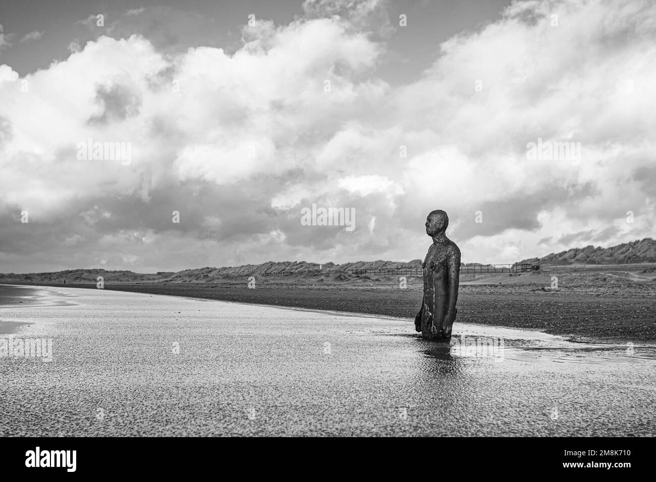 Un uomo di ferro sulla spiaggia di Crosby vicino a Liverpool visto nel gennaio 2023 in un lungo canale d'acqua. Foto Stock