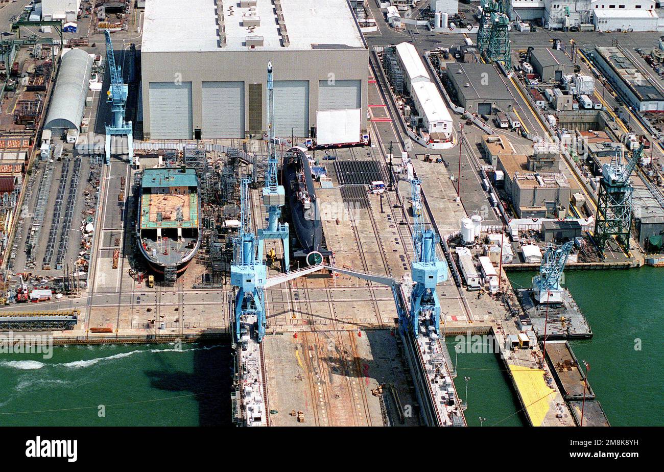 Una vista aerea a dritta di un quarto del sottomarino di attacco nucleare USS CHEYENNE (SSN-773) che poggia sulle vie dell'edificio di fronte all'edificio Module Outfitting presso la Newport News Shipbuilding e Drydock Corporation. Dietro il CHEYENNE c'è un traghetto commerciale in costruzione. Il CHEYENNE è il sessantesimo e ultimo sottomarino della classe di Los Angeles ad essere costruito. La nave è storta in bunting ed è pronta per il battesimo e il lancio. Base: Newport News Stato: Virginia (VA) Nazione: Stati Uniti d'America (USA) Foto Stock