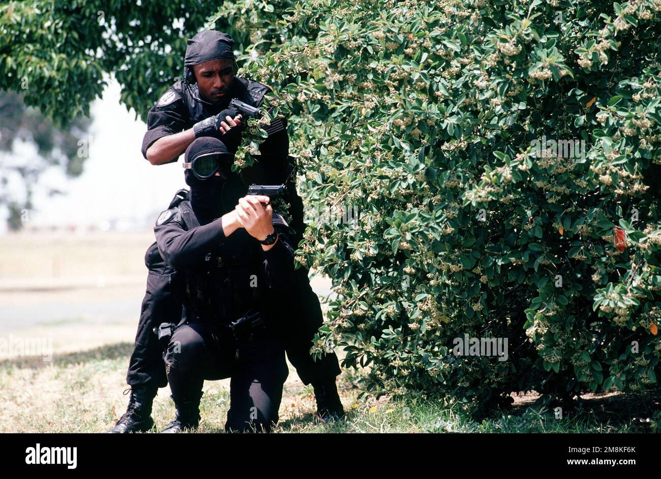 SRA Dave Orth (L) e SRA Clarence Tolliver (R), membri della squadra di scuderia di base della polizia di sicurezza 60th, Travis Air Force base indossa un supporto nero con pistole M-9 pronte dietro a coprire il fogliame. Partecipano a uno scenario di ostaggio simulato durante l'ispezione di preparazione operativa (ORI), che verifica la capacità di un'unità di operare in un ambiente simulato in tempo di guerra. Oggetto operativo/Serie: CRISIS REACH 95-02NORTHERN PIKE base: Travis Air Force base Stato: California (CA) Paese: Stati Uniti d'America (USA) Foto Stock