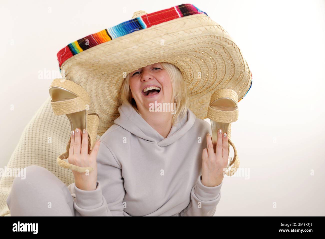 mexican Hat Dancing Dancing maturo donna messicana in sombrero cappello su sfondo bianco donna adulta tiene belle scarpe di paglia con tacco alto nelle sue mani, Foto Stock