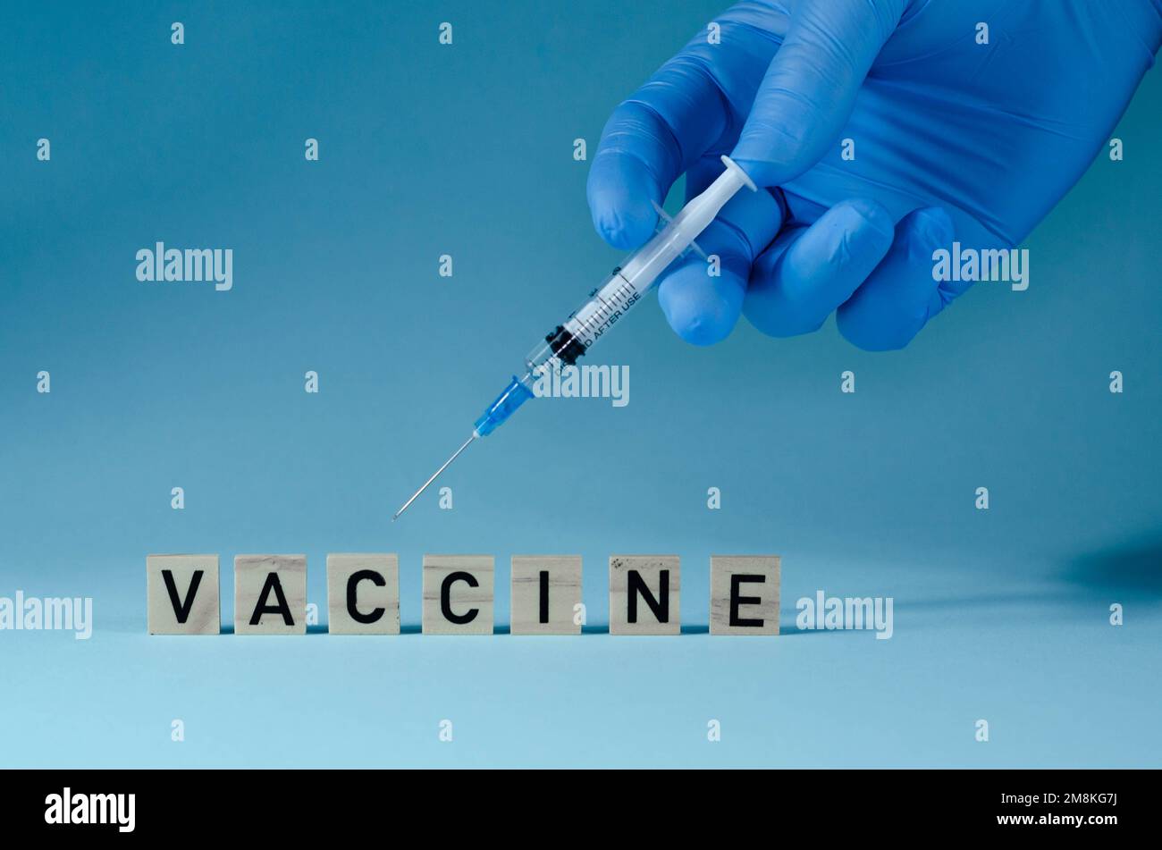 Medico in guanti di lattice blu con siringa, primo piano. Effettuare un'iniezione di vaccino. Contagio, incubazione, dices lettera su siringa. Foto Stock