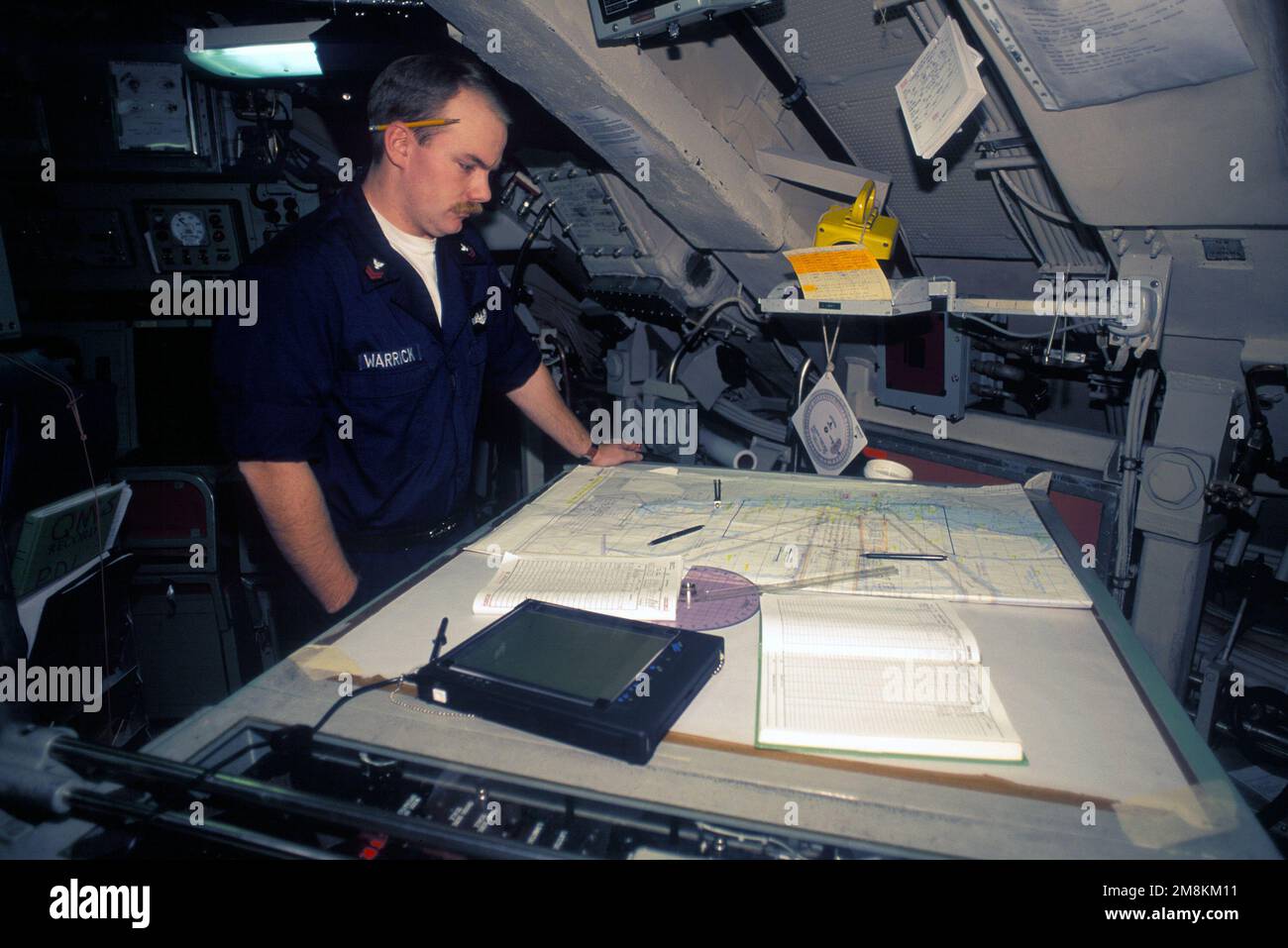 Quartermaster seconda Classe (QM2) Warrick controlla la carta di navigazione nella tabella di tracciamento del centro di controllo della nave del sottomarino missilistico balistico nucleare USS PENNSYLVANIA (SSBN-735). Paese: Sconosciuto Foto Stock