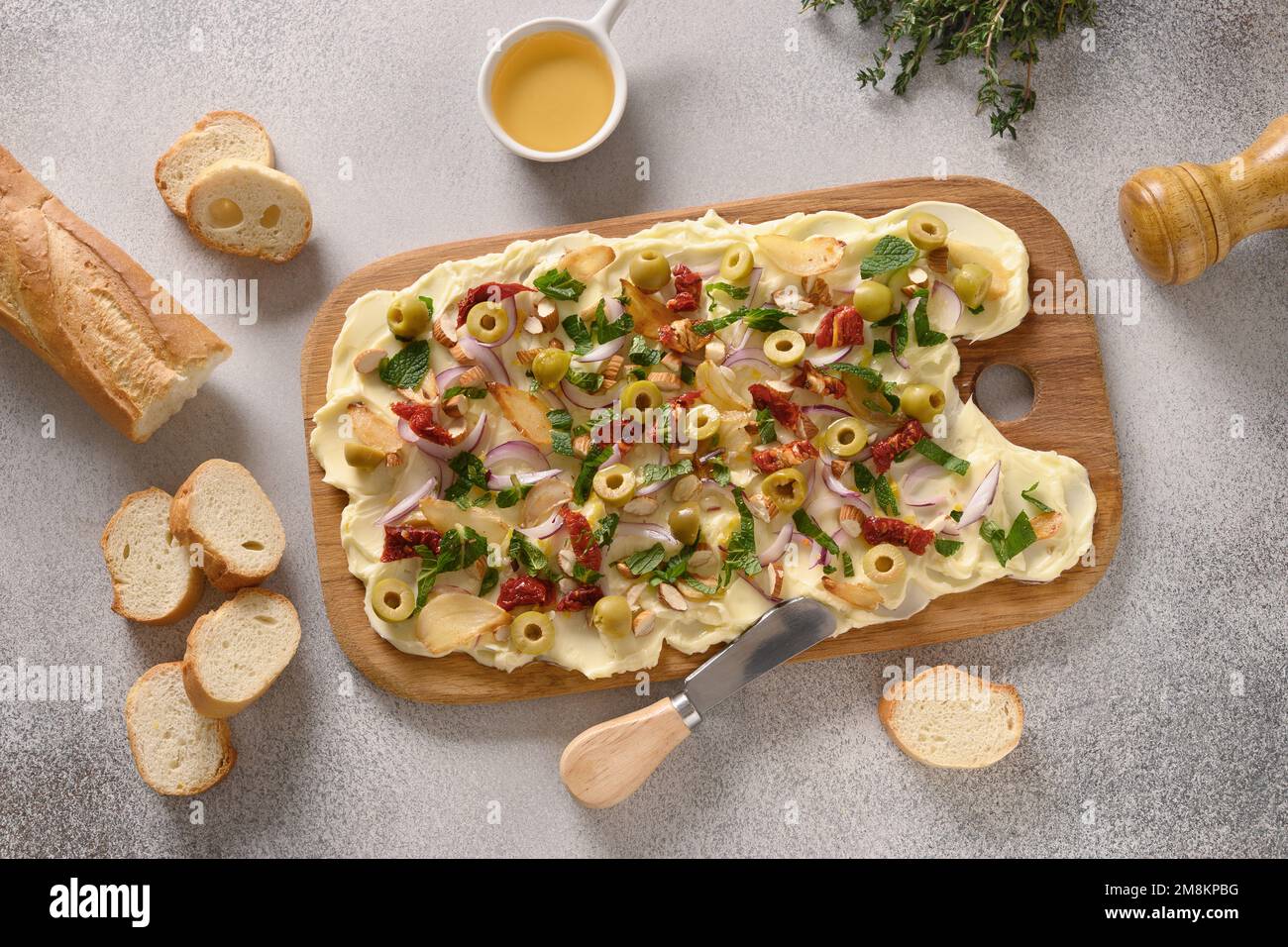 Popolare Butterboard con pomodori secchi al sole, timo, cipolla, aglio su sfondo grigio. Vista dall'alto. Foto Stock