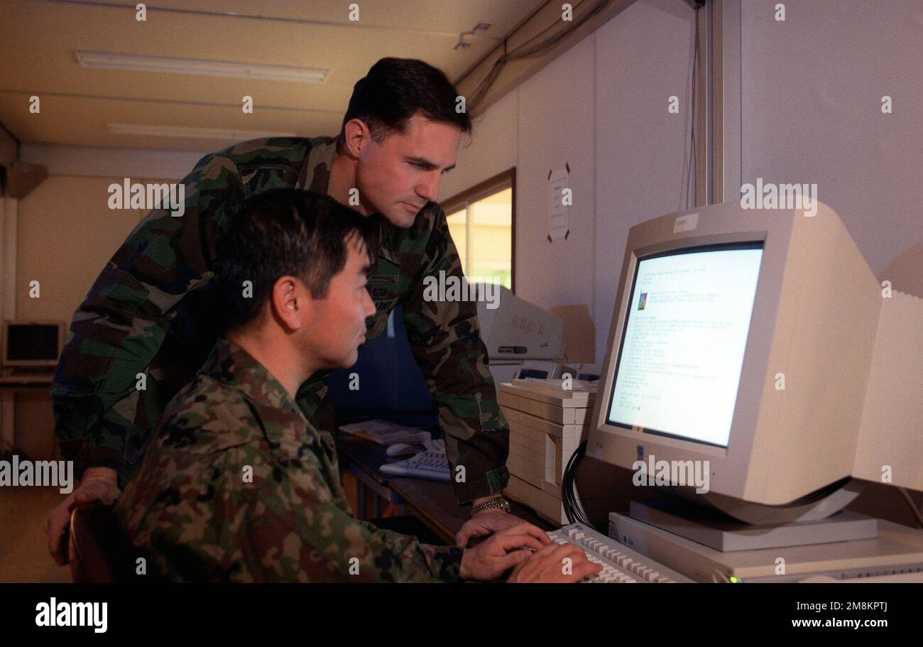 United States Forces Giappone (USFJ) Army MAJ Daniel Baggio guarda su come Giappone Ground Self Defense Force (JGSDF) LTCOL Seijiro Kiyomichi monitora le azioni mentre prova il sistema Joint Theater Level Simulation (JTLS) alla base aerea di Yokota, Giappone. I membri del servizio della USFJ e della JSDF svolteranno un'esercitazione congiunta/bilaterale, Keen Edge '96, presso le installazioni militari statunitensi e giapponesi dal 25 gennaio al 2 febbraio 1996. Soggetto operativo/Serie: KEEN EDGE '96 Paese: Sconosciuto Foto Stock