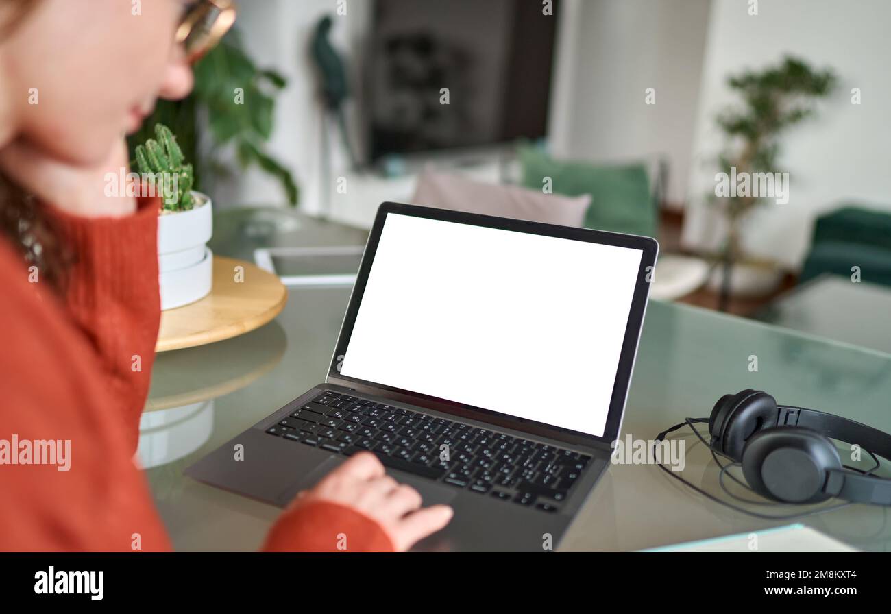 Vista a spalla della donna elearning guardando lo schermo mock-up utilizzando un notebook. Foto Stock