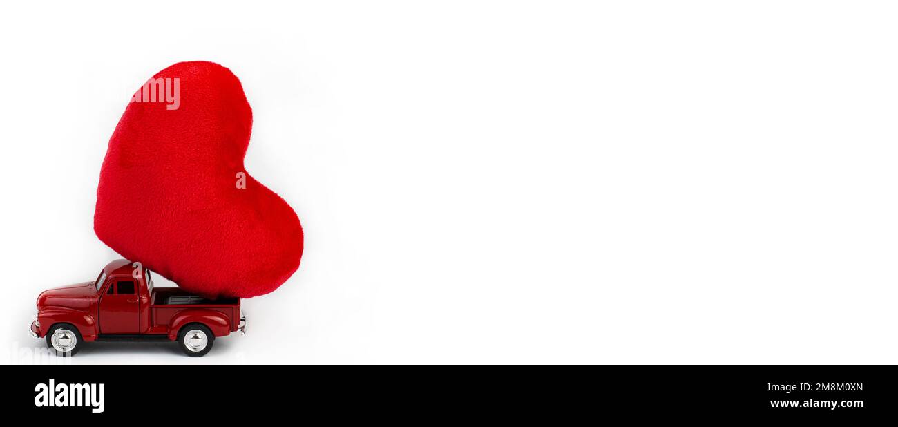San Valentino. Un'auto rossa porta un cuore su uno sfondo bianco. Banner largo Foto Stock