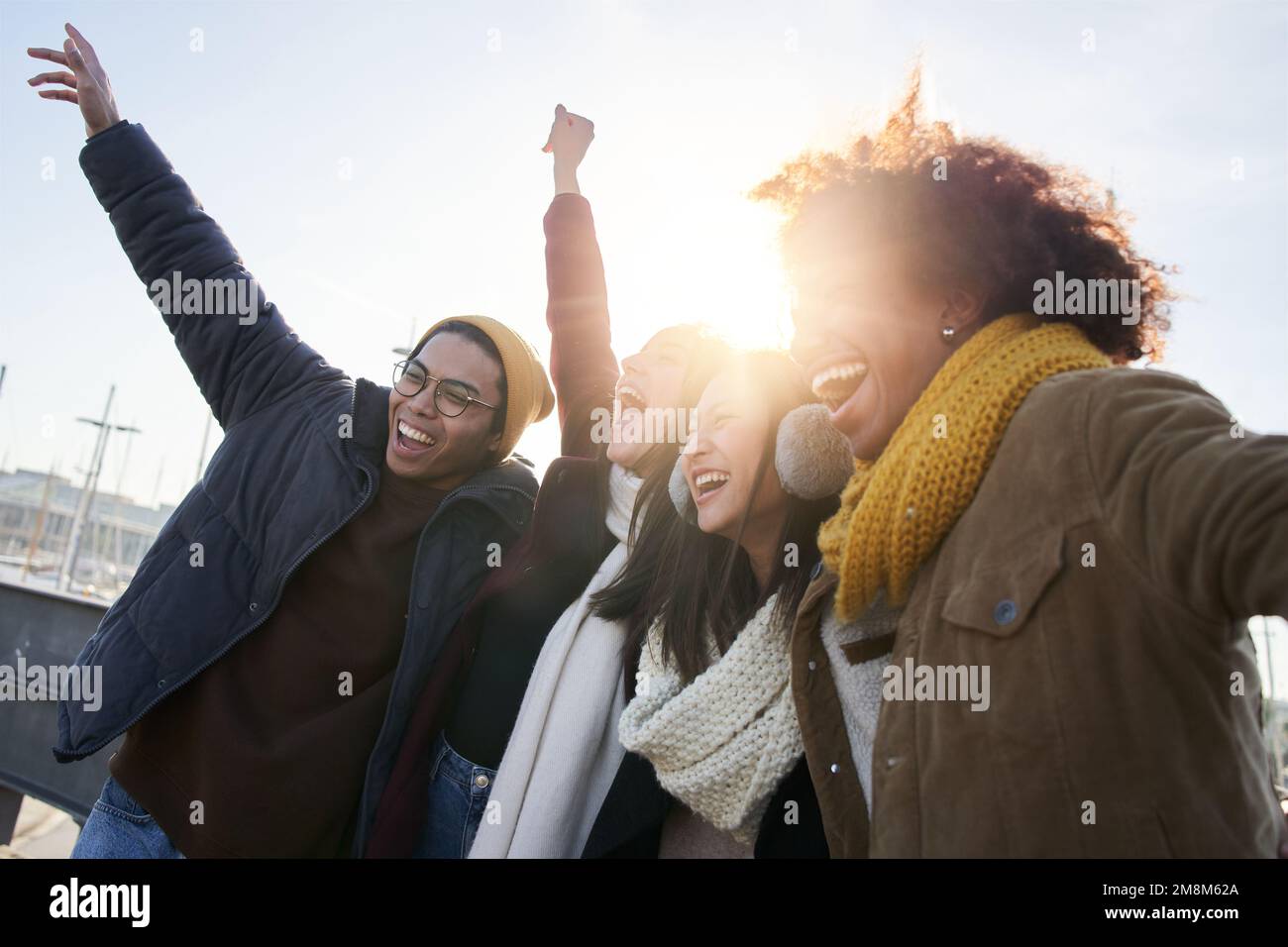 Gruppo di giovani amici entusiasti che si divertono insieme all'aperto. Persone diverse abbracciano e ridono godere Foto Stock