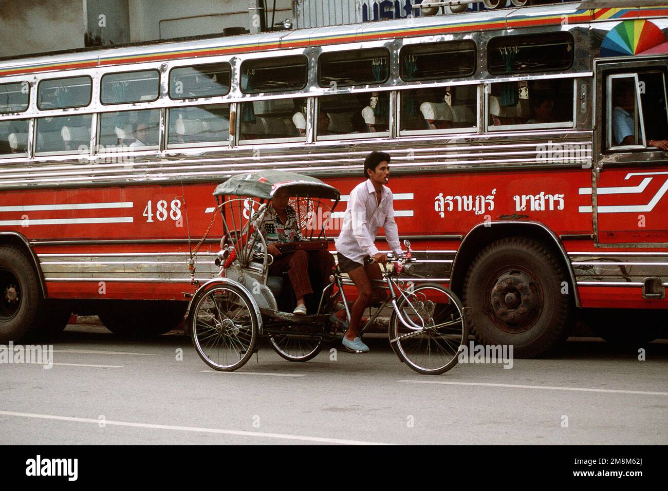 I tradizionali carrelli per biciclette e gli autobus moderni coesistono vicino alla giungla dove si svolge Cobra Gold. Exact Date Shot Unknown pubblicato su AIRMAN Magazine Agosto 1996. Subject Operation/Series: COBRA GOLD '96 base: Surat Thani Paese: Thailandia (THA) Foto Stock