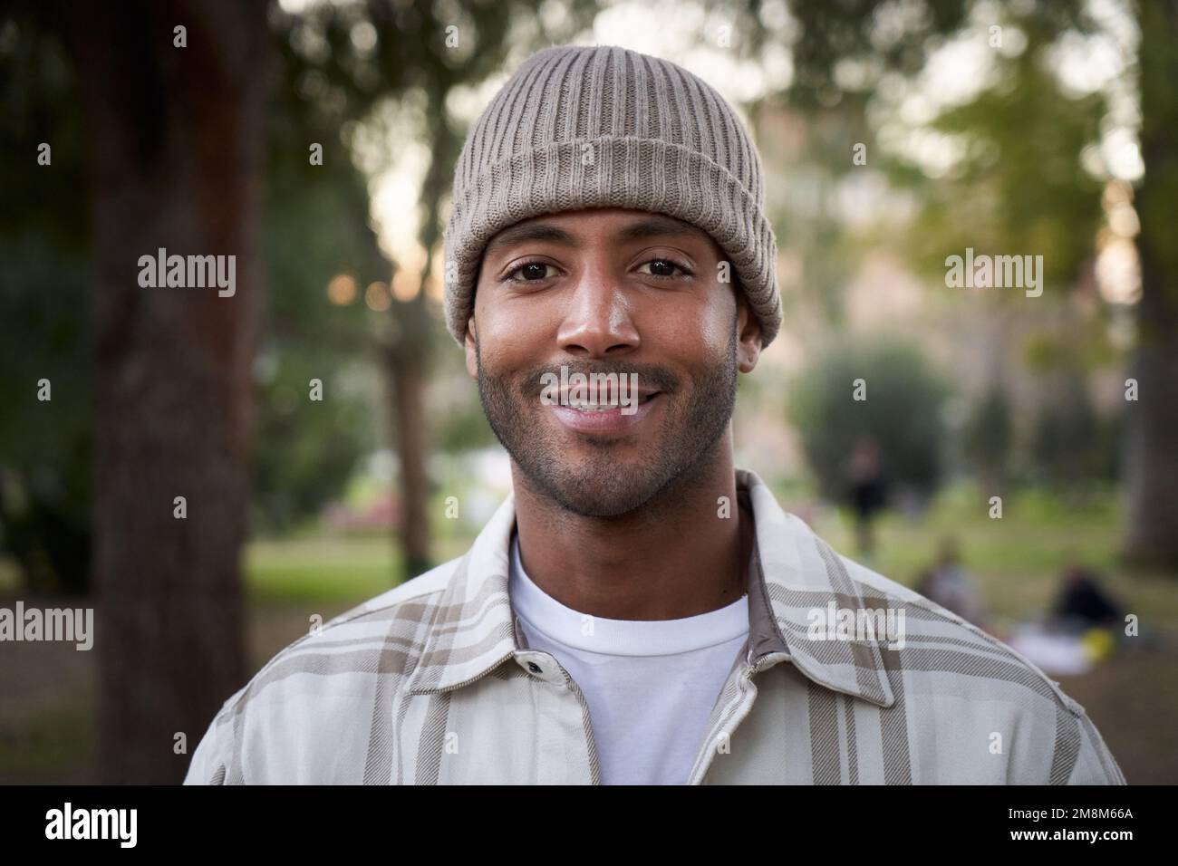 Ritratto di bel giovane africano sorridente con cappello a maglia che guarda camera espressione positiva Foto Stock