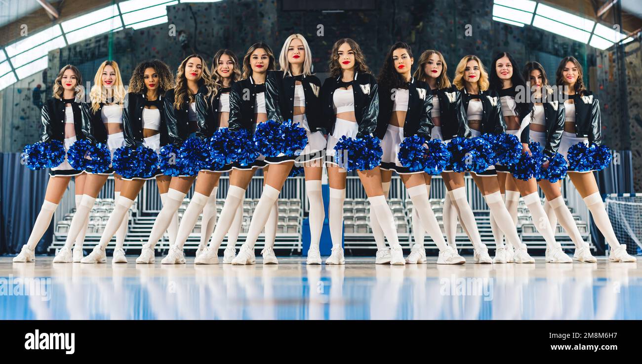 Cheerleaders in mini-gonne catturato ad un angolo basso mentre si levano in piedi con pom-pom. Foto di alta qualità Foto Stock