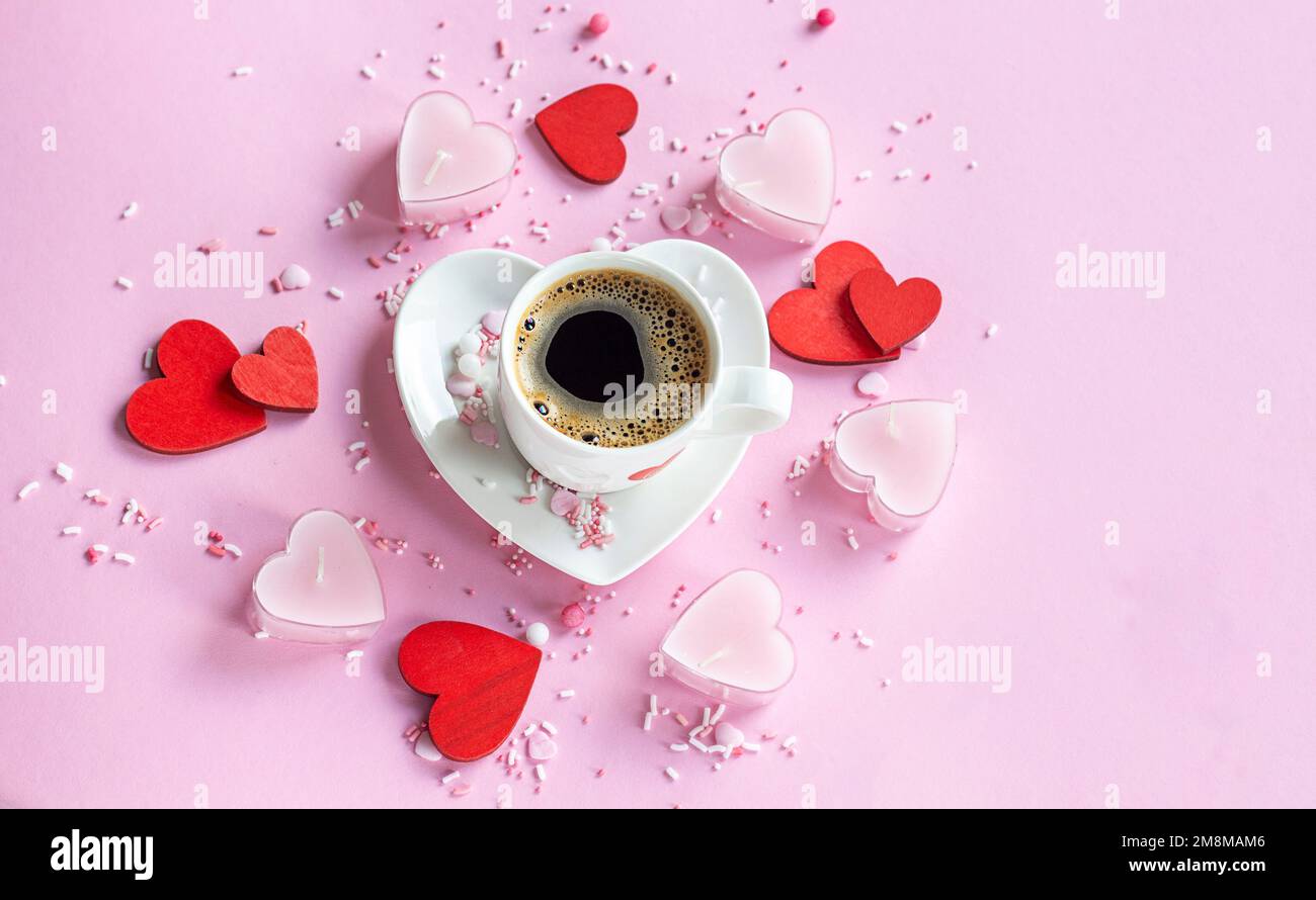Chicchi di caffè aromatici. Caffè il giorno di San Valentino su uno sfondo rosa, candele cuore rosa. caffè. copyspace. Foto Stock