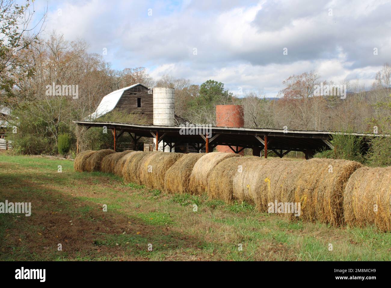 Balle di fieno con vecchio fienile e silos Foto Stock