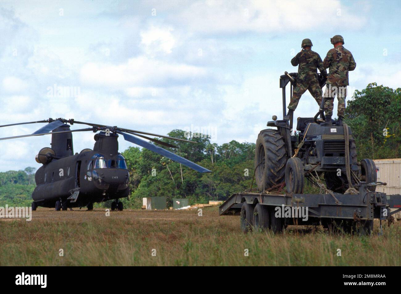 IL SENIOR AIRMAN Michael Hafstad e IL SENIOR AIRMAN Adrian Faison, entrambi ingegneri strutturali dello Squadrone a cavalli rossi del 820th, la base dell'aeronautica militare di Nellis, Nevada, si trovano in cima a un trattore su un rimorchio che verrà caricato sull'elicottero CH-47 Chinook in background. Il CH-47 ridistribuirà le attrezzature da Kumaka a Camp Stephenson, Timehri Guyana. Il 820th, è stato a Kumaka per rinnovare l'ospedale regionale esistente come parte di questo primo esercizio combinato di assistenza umanitaria e civile condotto tra gli Stati Uniti e la Guyana. Personale militare dell'Aeronautica militare, della Riserva dell'Aeronautica Foto Stock