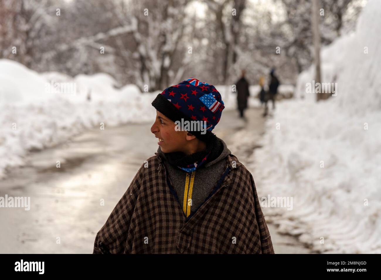 Srinagar, India. 15th Jan, 2023. Un ragazzo si guarda mentre cammina lungo una strada dopo una forte nevicata nella periferia di Srinagar. A causa delle forti nevicate, ci sono state valanghe multiple in diversi luoghi del Kashmir. Il periodo di 40 giorni dal 21 dicembre al 31st gennaio, noto anche come Chilai Kalan, in Kashmir è considerato il più cruciale quando nevica la condizione peggiora ulteriormente. (Foto di Idrees Abbas/SOPA Images/Sipa USA) Credit: Sipa USA/Alamy Live News Foto Stock