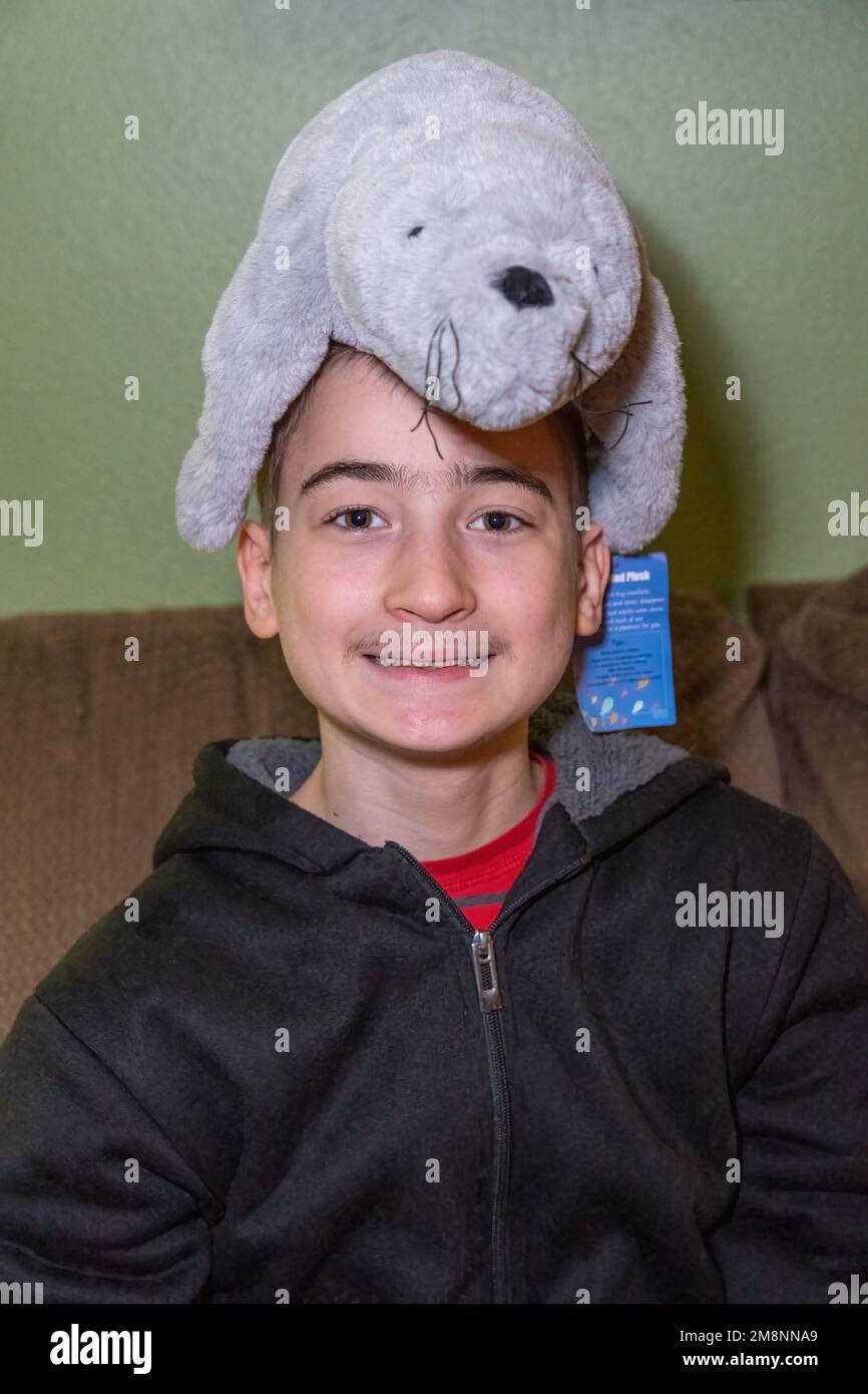 ragazzo di 14 anni che agisce sciocco con un animale ripieno appena acquistato sulla sua testa. (SIG.) Foto Stock