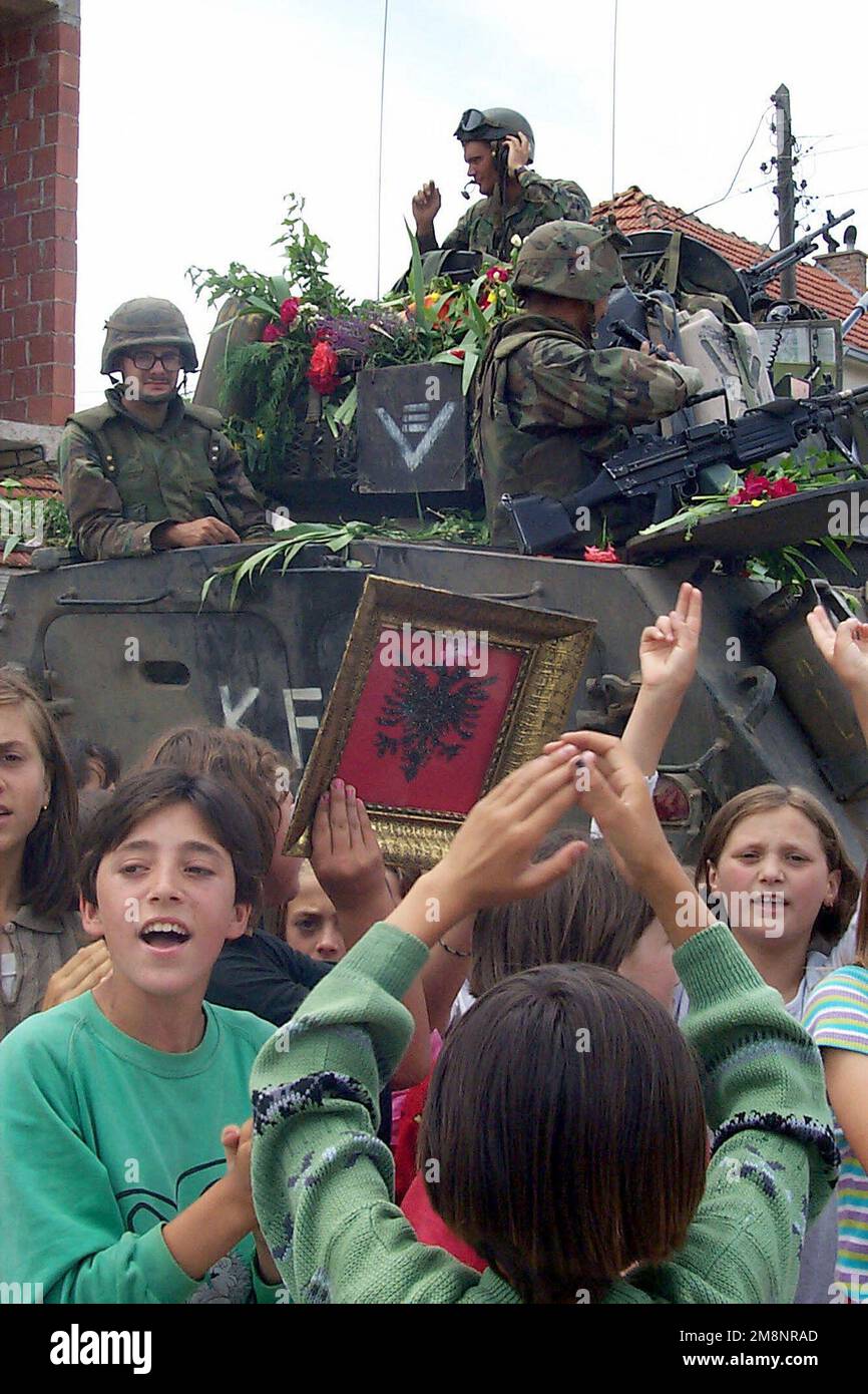 STATI UNITI I marines della 26th Marine Expeditionary Unit (MEU), 3rd battaglione, 8th marines, in cima a un portatore di personale blindato, ricevono un caloroso benvenuto con rose e cantano i bambini di una città locale vicino alla base operativa in Kosovo. Gli elementi del 26th MEU dispiegati dalle navi del gruppo 2 di preparazione anfibio (non mostrato) a sostegno dell'operazione guidata dalla NATO Joint Guardian. Oggetto/Serie: STATO CUSTODE CONGIUNTO: Kosovo Paese: Jugoslavia (YUG) Foto Stock