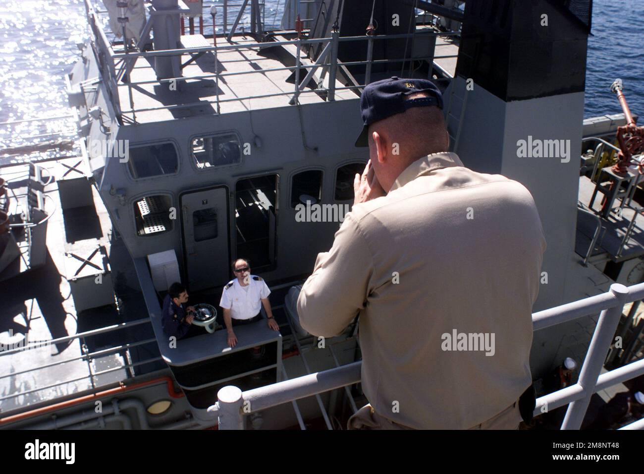 US Navy Lieutenant Commander Michael Skelly, Executive Officer di USS REUBEN JAMES (FFG 57) grida sopra il rumore al funzionario responsabile del Tang cileno oceano GALVARINO (ATF 66) durante le operazioni di rifornimento mentre ancorato al largo della città portuale di Antofagasta, Cile, durante l'esercizio DI SQUADRA SUD '99. Subject Operation/Series: LAVORO DI SQUADRA SOUTH '99 base: Antofagasta Nazione: Cile (CHL) Foto Stock