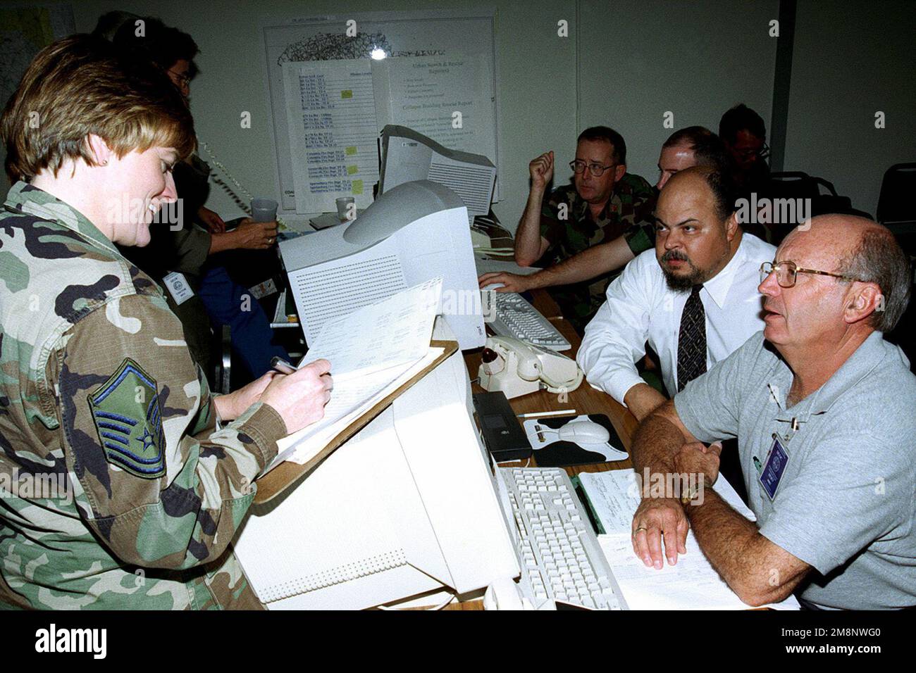 MASTER Sergente Linda Coleman, South Carolina Air National Guard, lavora con altri personale di soccorso in caso di uragano Floyd presso la South Carolina Emergency Prepardness Division. In background il maggiore Cal Hodges, 169th Communications Flight Commander, SC Air National Guard, lavora la scrivania delle comunicazioni con il suo omologo della Guardia Nazionale dell'Armata. Entrambe le organizzazioni fanno parte del Dipartimento militare della Carolina del Sud, 15 settembre 1999. Stato: South Carolina (SC) Paese: Stati Uniti d'America (USA) Foto Stock