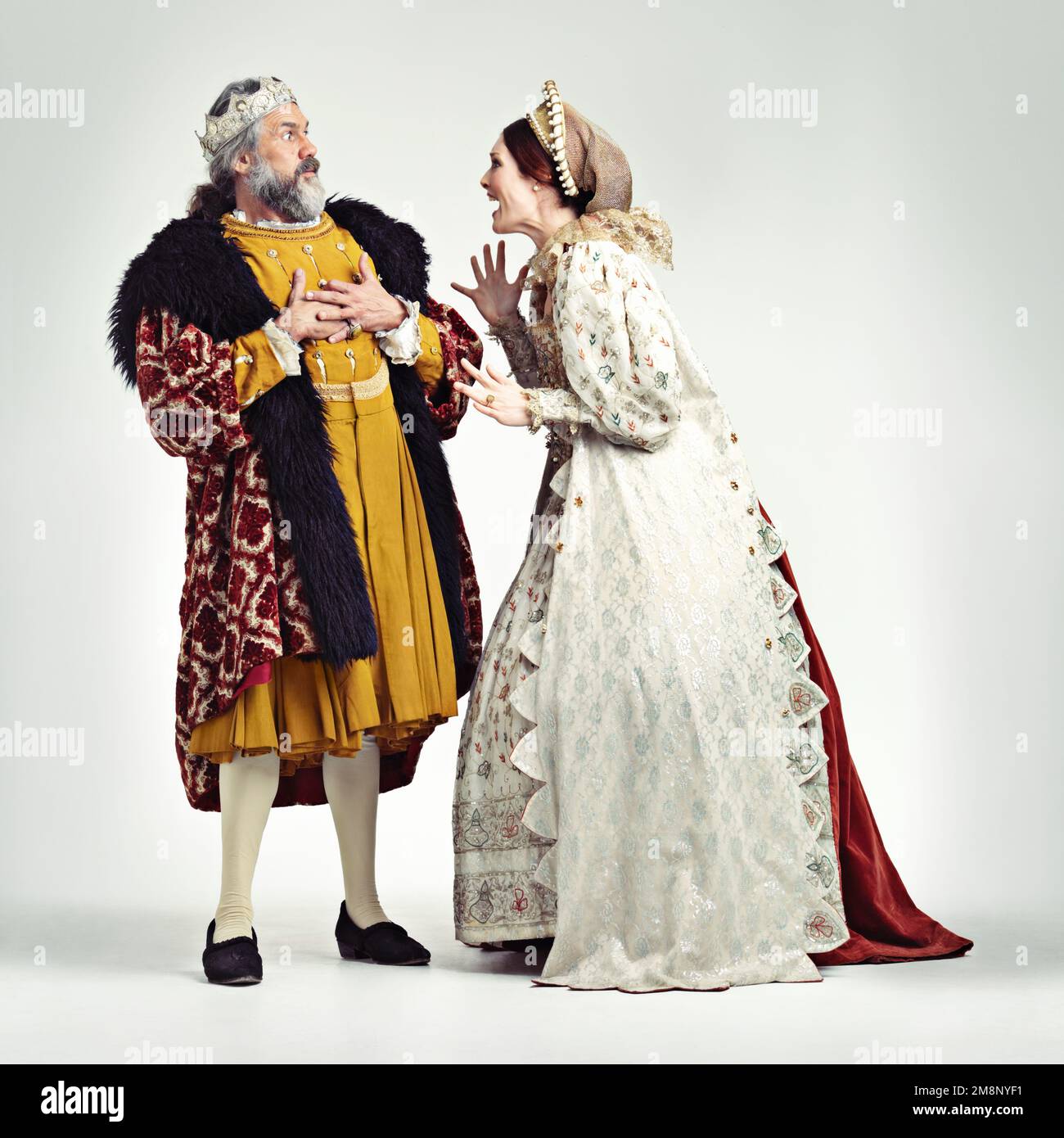 Argomentare, medievale e re con la regina su uno sfondo bianco per argomento, rabbia e frustrata lotta. Storia, teatro e coppia reale in vintage Foto Stock