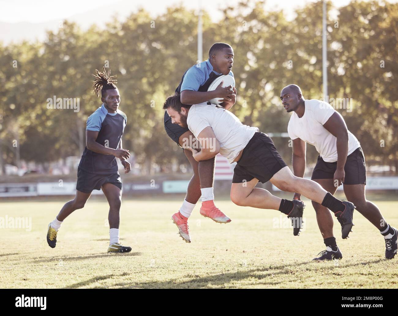Giocatore di rugby caucasico che tenta di affrontare un avversario durante una partita di rugby fuori sul campo. Giovane atletico che affronta un avversario in un Foto Stock