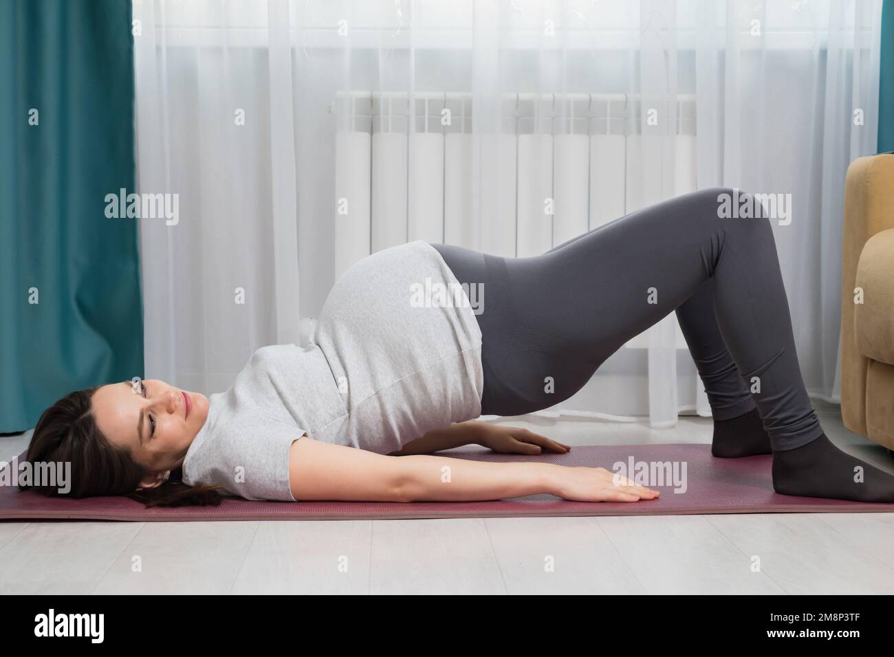 Donna incinta che fa pilates su tappetino viola a casa Foto Stock