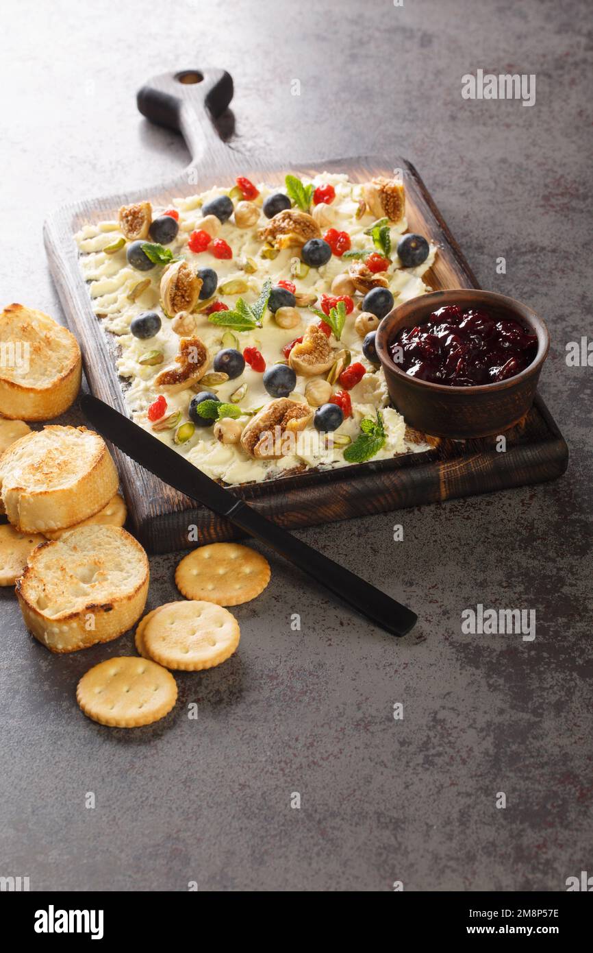 Tendenza alimentare burro bordo, burro spalmato su legno con condimenti dolci primo piano sul tavolo. Verticale Foto Stock